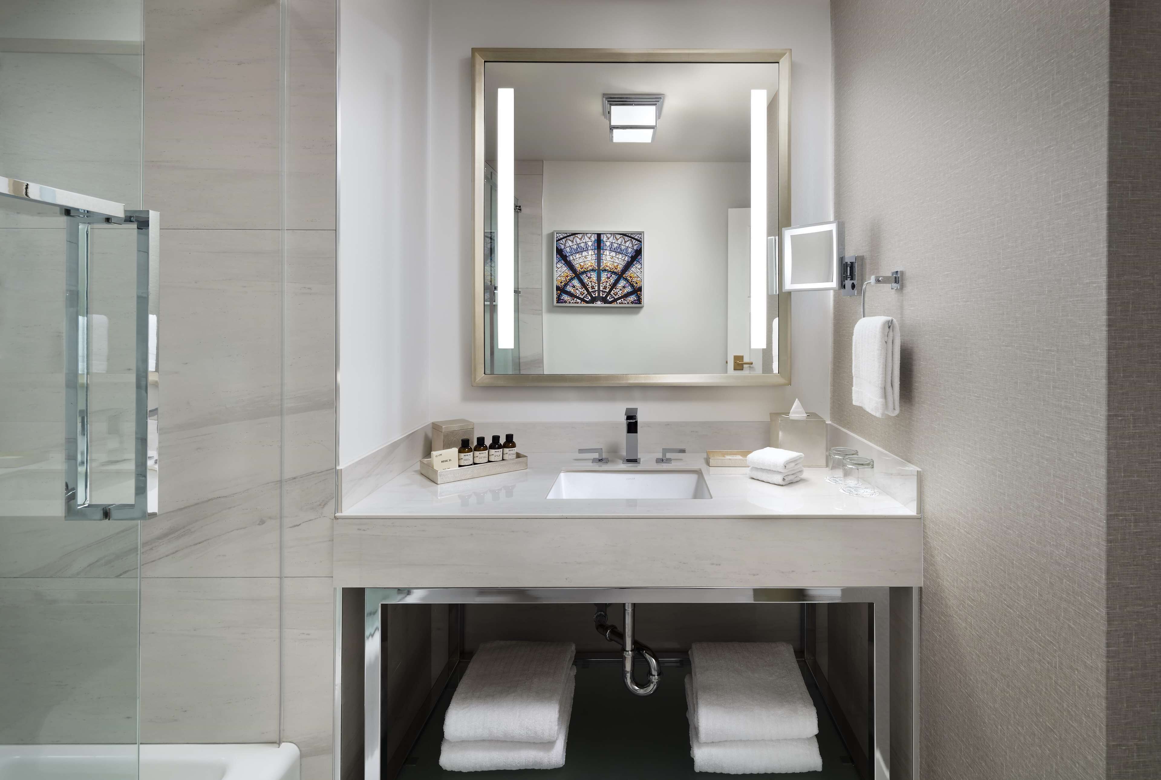 Un baño moderno con un espejo grande, un lavabo y una cabina de ducha de vidrio.