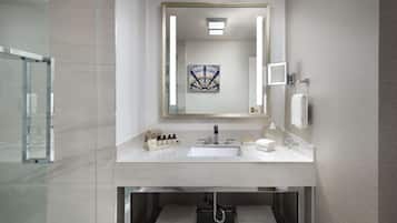 A modern bathroom with a large mirror, a sink, and a glass shower enclosure.