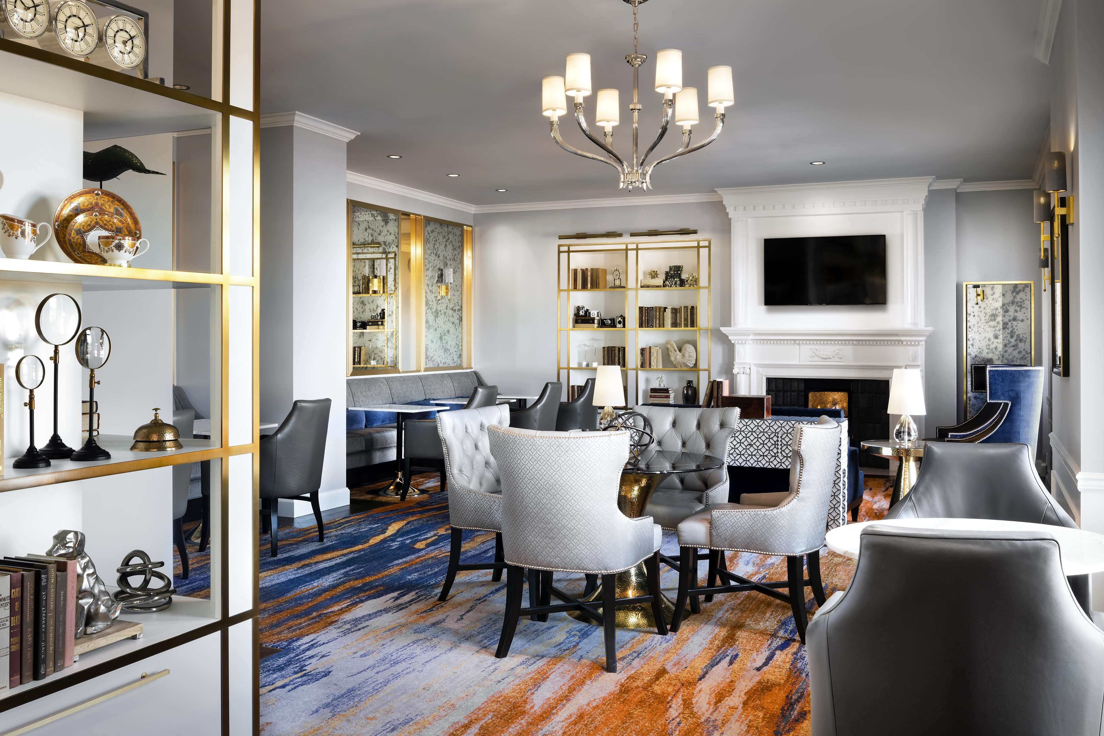 A modern living room with a fireplace, a chandelier, and a television mounted on the wall.