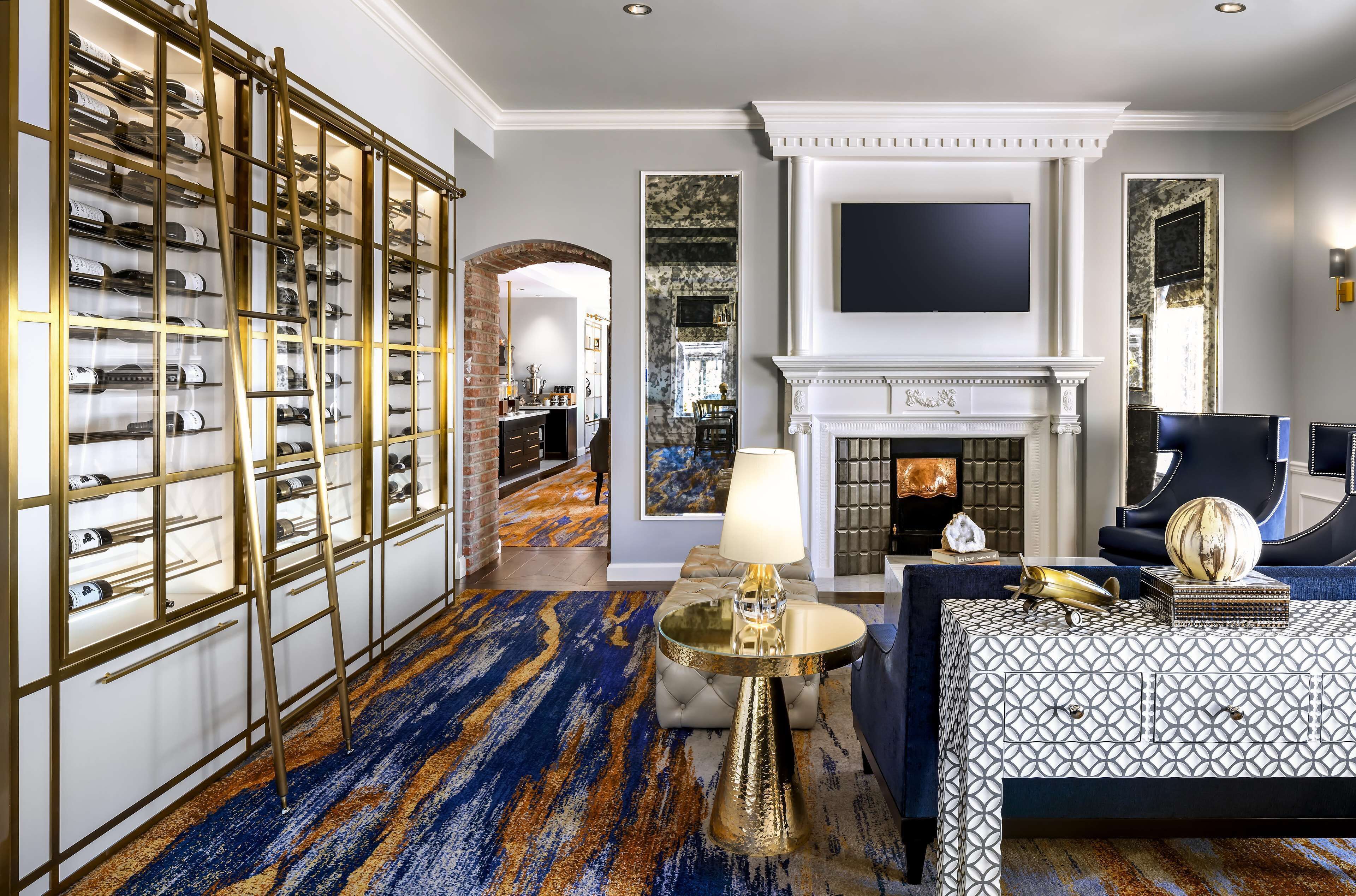A luxurious room with a wine rack, a fireplace, a television, and a patterned bedspread.