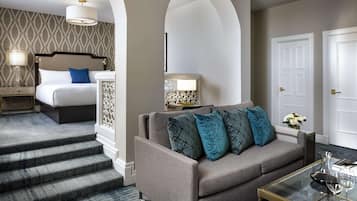 A hotel room with a bed, a sofa, a coffee table, and a staircase.