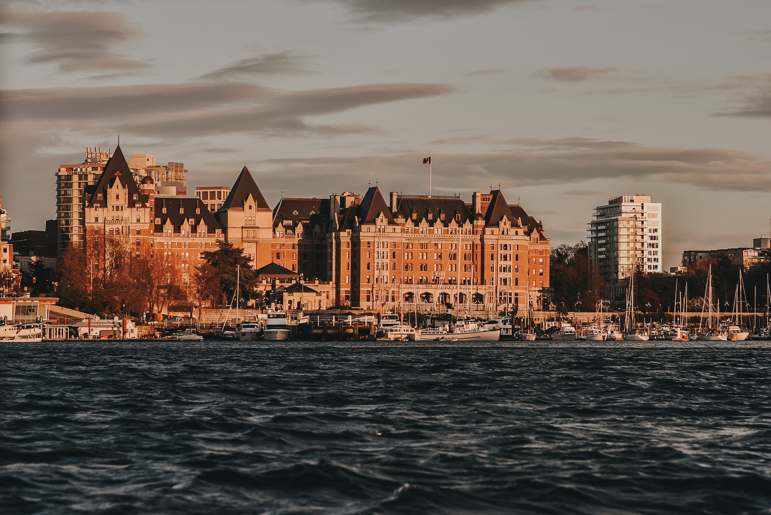 A waterfront hotel with a prominent building featuring a large tower and multiple windows.