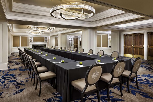 A conference room with a long table, chairs, and a chandelier.