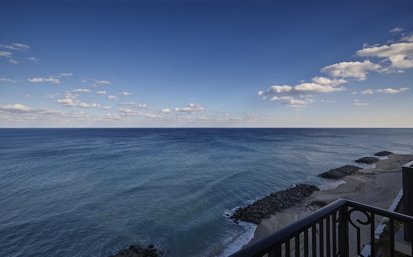 A coastal view with a clear sky, calm sea, and rocky shoreline. - The Breakers Palm Beach (Palm Beach)