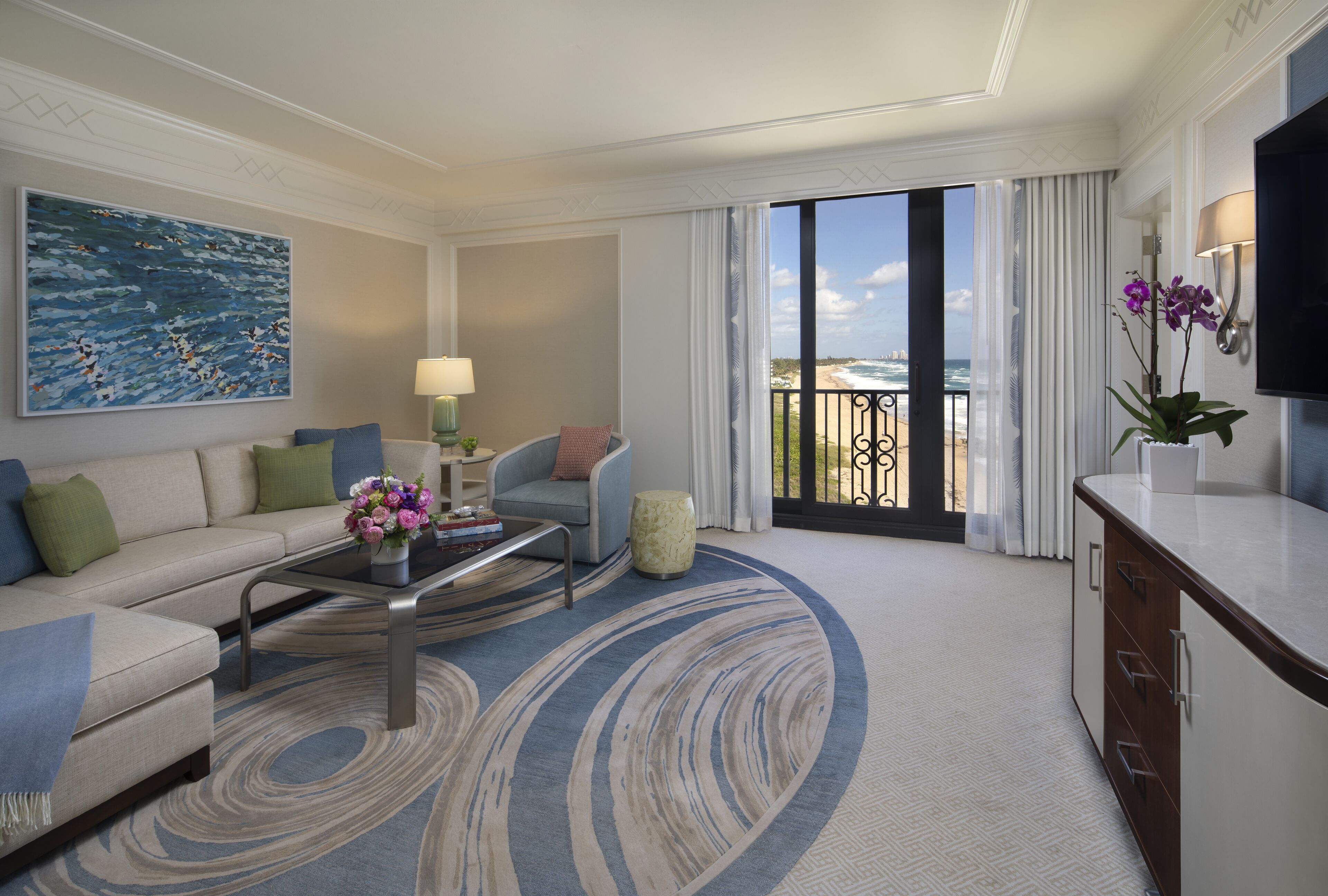 Une chambre d’hôtel moderne avec un canapé, une table basse et vue sur la plage.