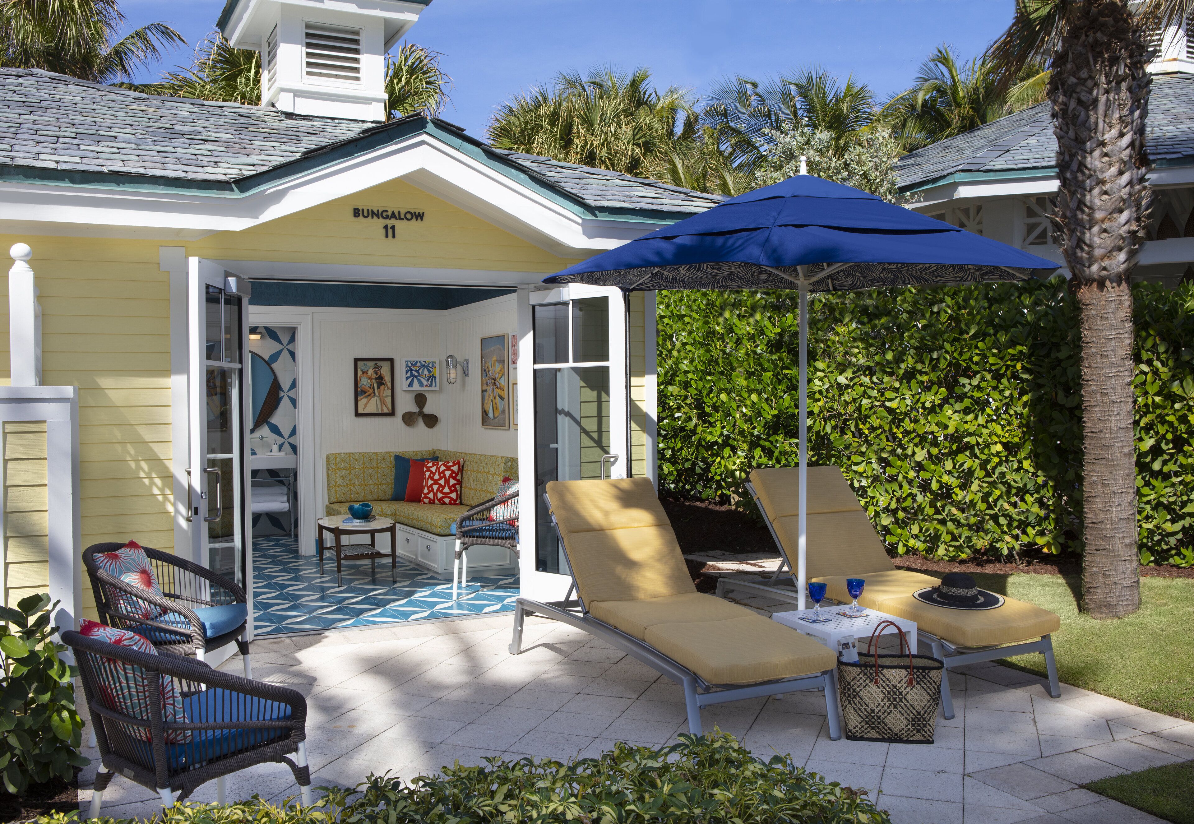 Un bungalow doté d’un patio comprenant des chaises longues, une table et un parasol.