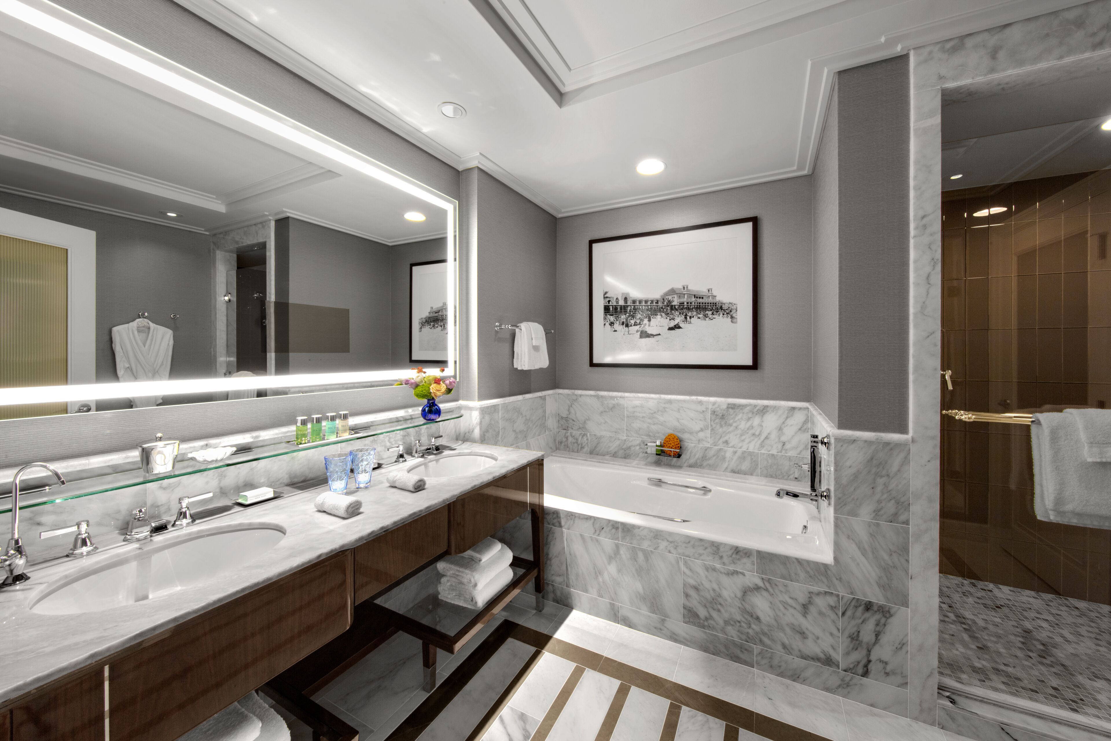 A modern bathroom with two sinks, a large mirror, and a bathtub.