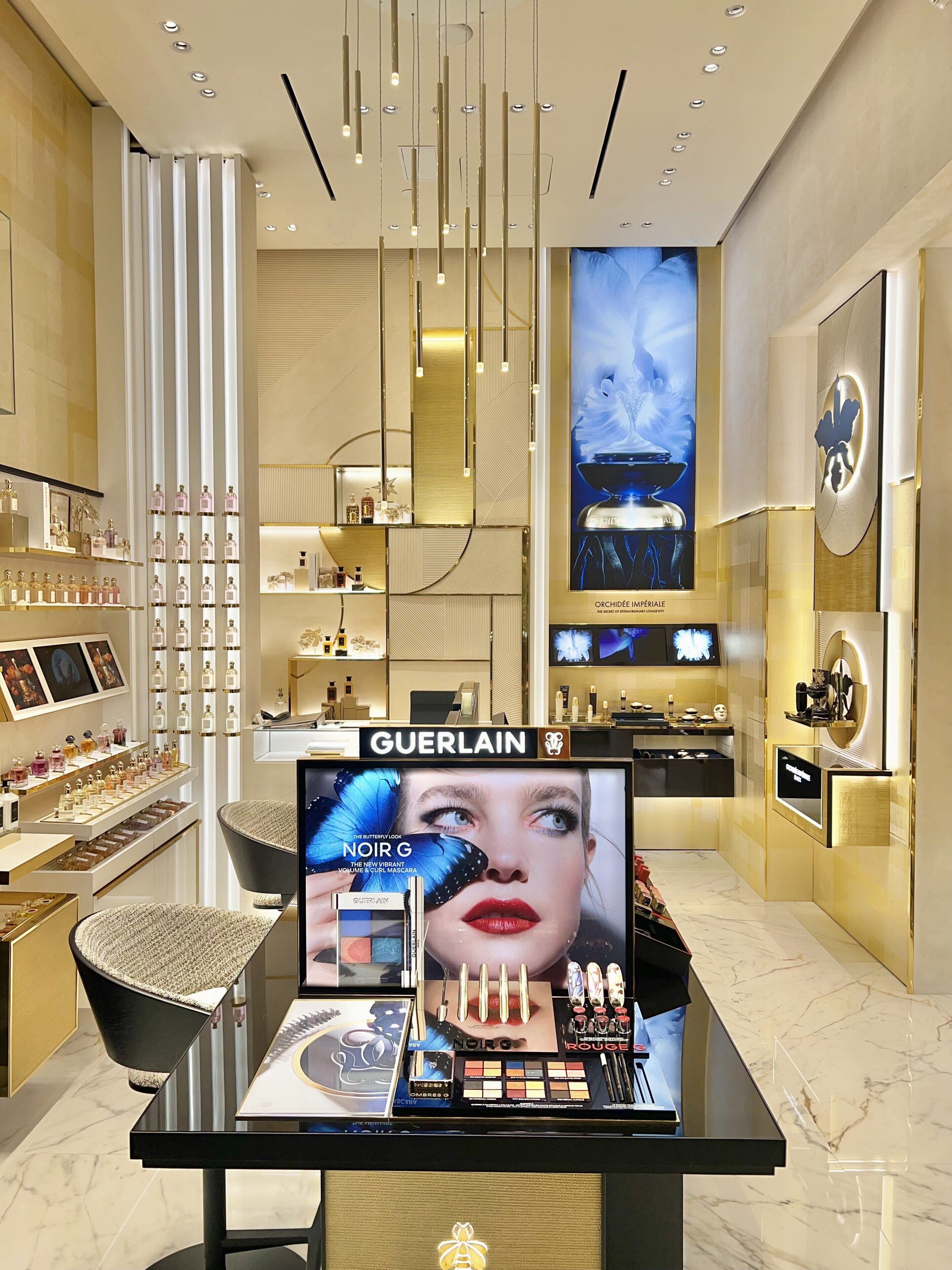 A Guerlain perfume display with a large advertisement for 'Noir G' and 'Rouge'.