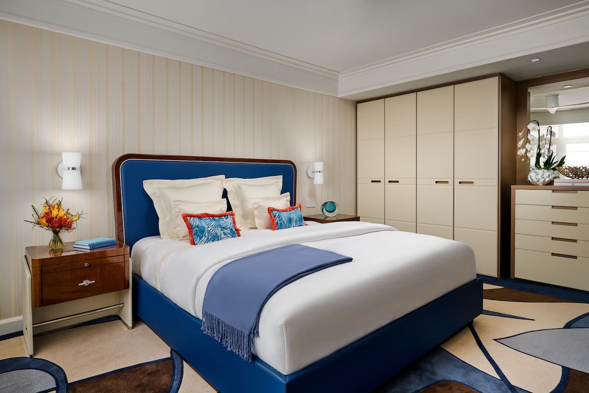 Una habitación de hotel con una cama grande, una mesita de noche con lámpara, un aparador y un espejo.