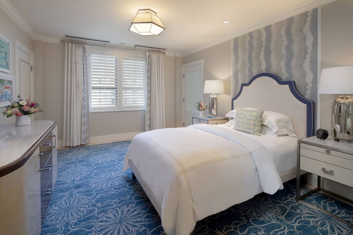 Habitación de hotel con una cama grande, una mesita de noche, un escritorio y una ventana con cortinas.