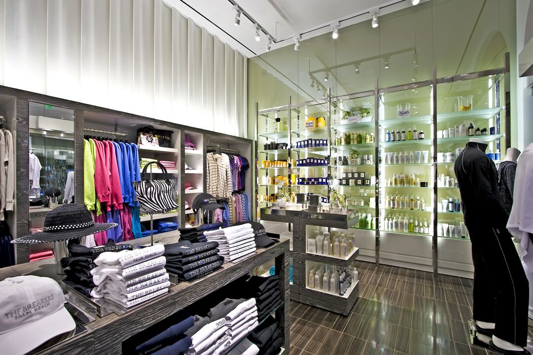 A clothing store with racks of folded clothes, shelves of bottles, and a mannequin.