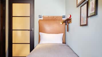 A hotel room with a bed, a wooden headboard, a clock, and framed artwork on the wall.