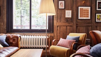 Una habitación acogedora con un sofá de cuero, una mesa de madera, una lámpara de pie y un radiador.
