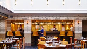 Interior de un restaurante con paredes de ladrillo, mesas y sillas de madera.