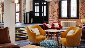 Un interior moderno con una escalera, sillones amarillos, sofás rojos y una mesa de madera.