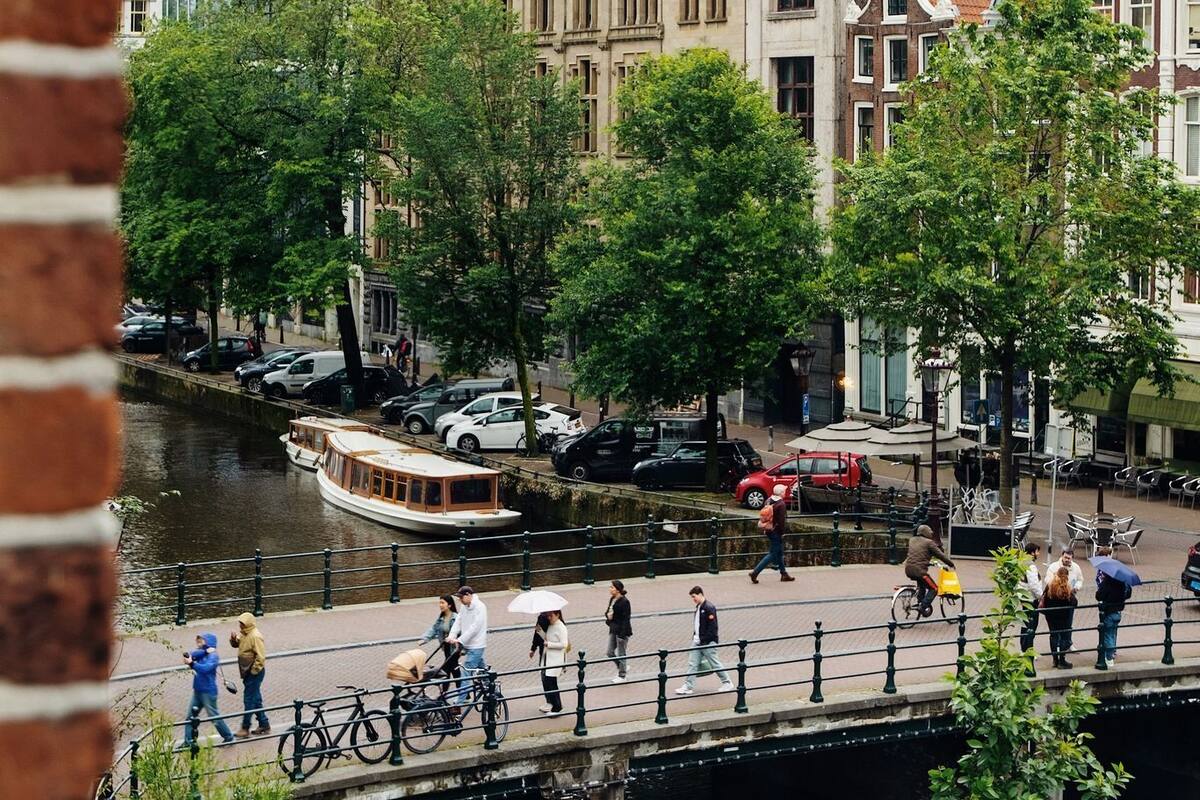 Un paseo a orillas de un canal, con edificios históricos, un puente y una barca amarrada al agua.