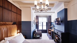 Habitación de hotel con una cama grande, un escritorio, un televisor y una ventana con cortinas.