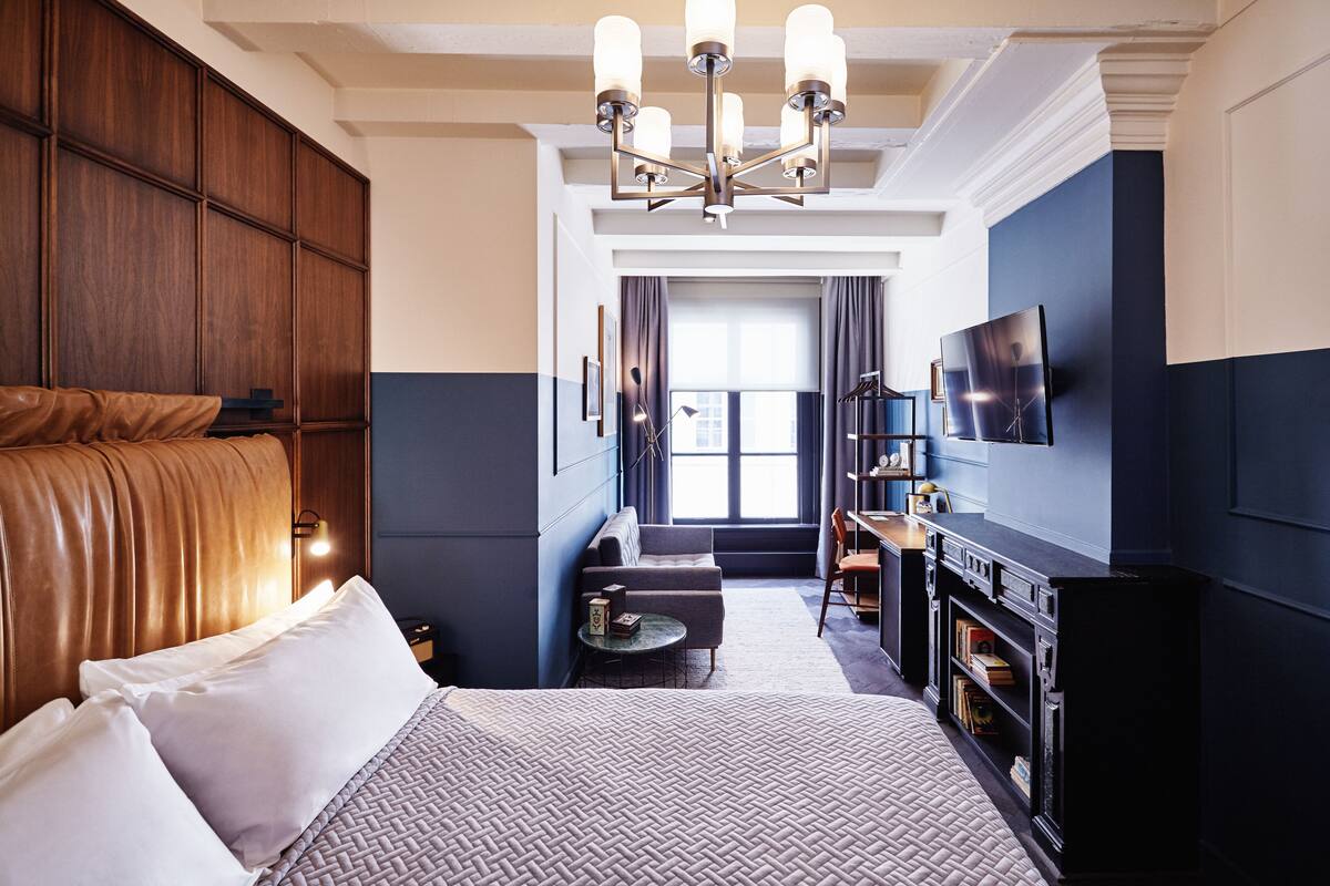 Habitación de hotel con una cama grande, un escritorio, un televisor y una ventana con cortinas.