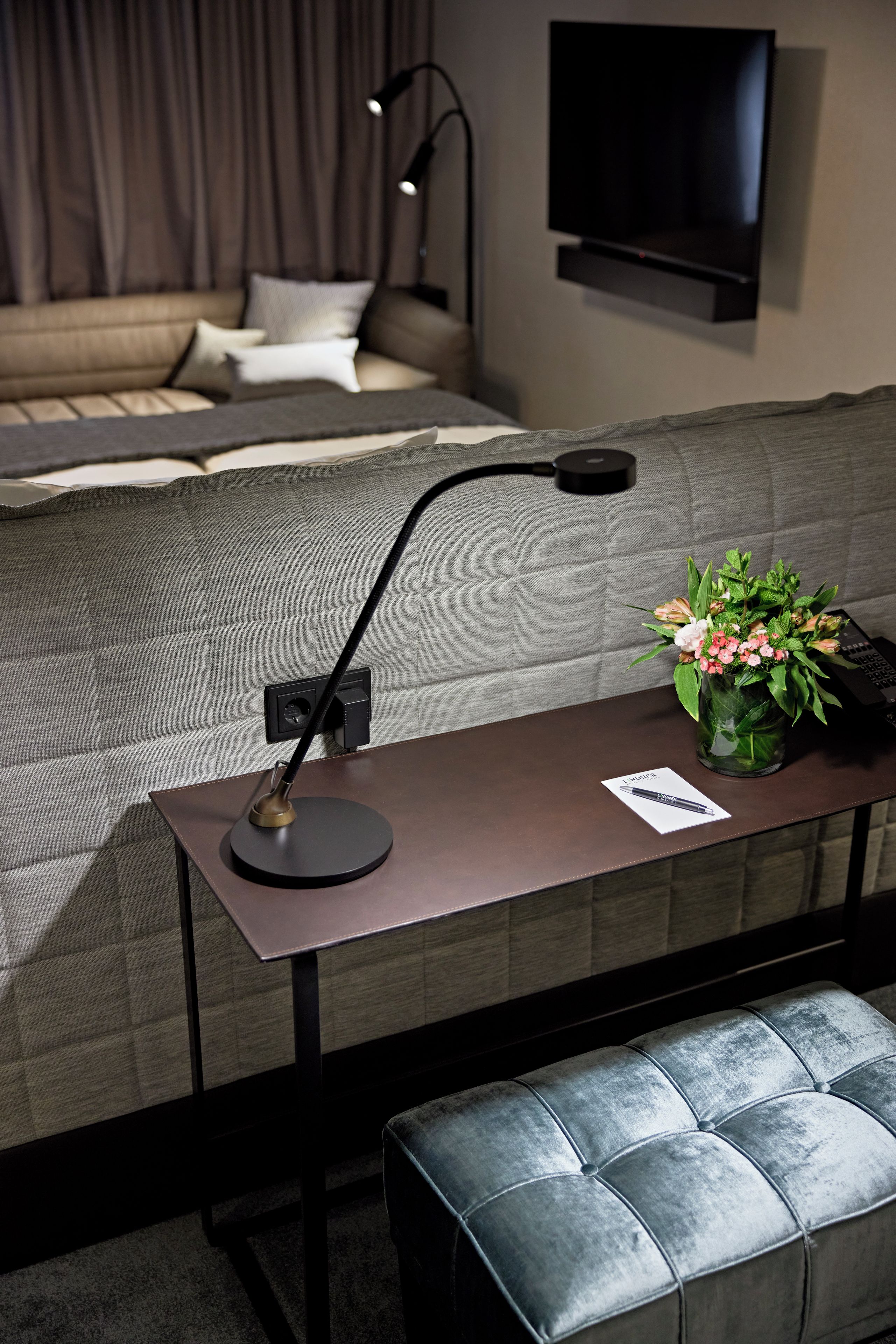 A modern living room with a sofa, a coffee table with a lamp, a laptop, and a potted plant.