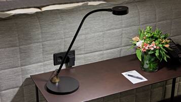 A modern living room with a sofa, a coffee table with a lamp, a laptop, and a potted plant.