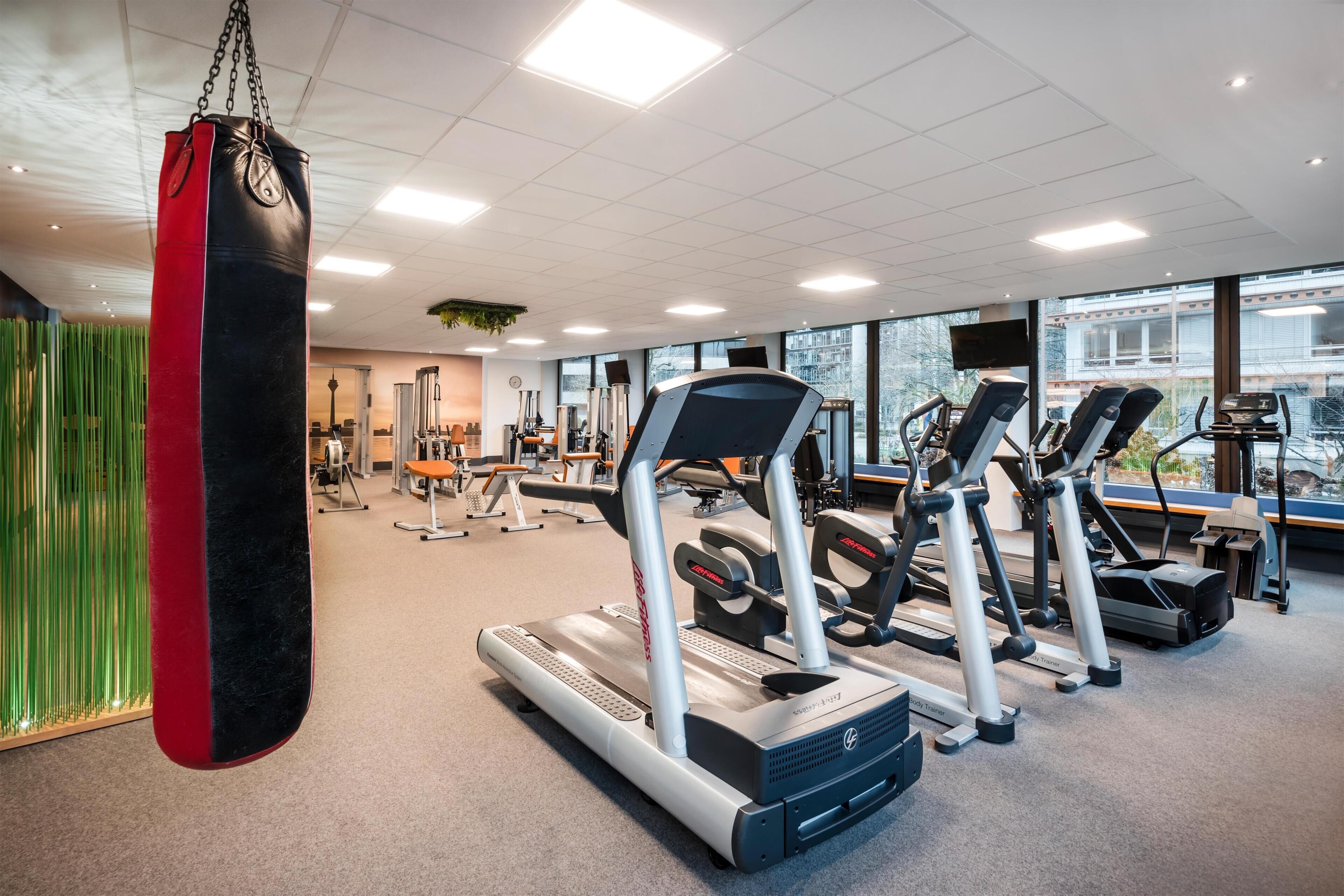 Una palestra con tapis roulant, macchinari per l'allenamento e un sacco da boxe.