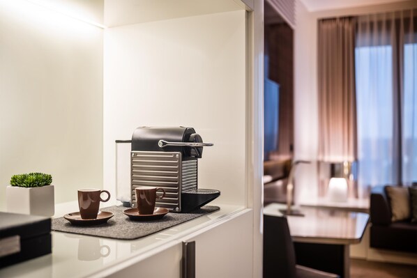 Una kitchenette con cafetera, dos tazas y una pequeña planta.