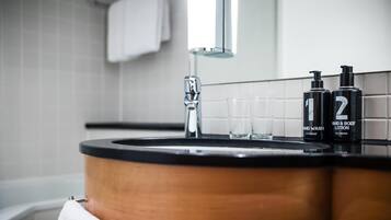 Un baño con un lavamanos de madera, un espejo y dos botellas de loción corporal y para manos.