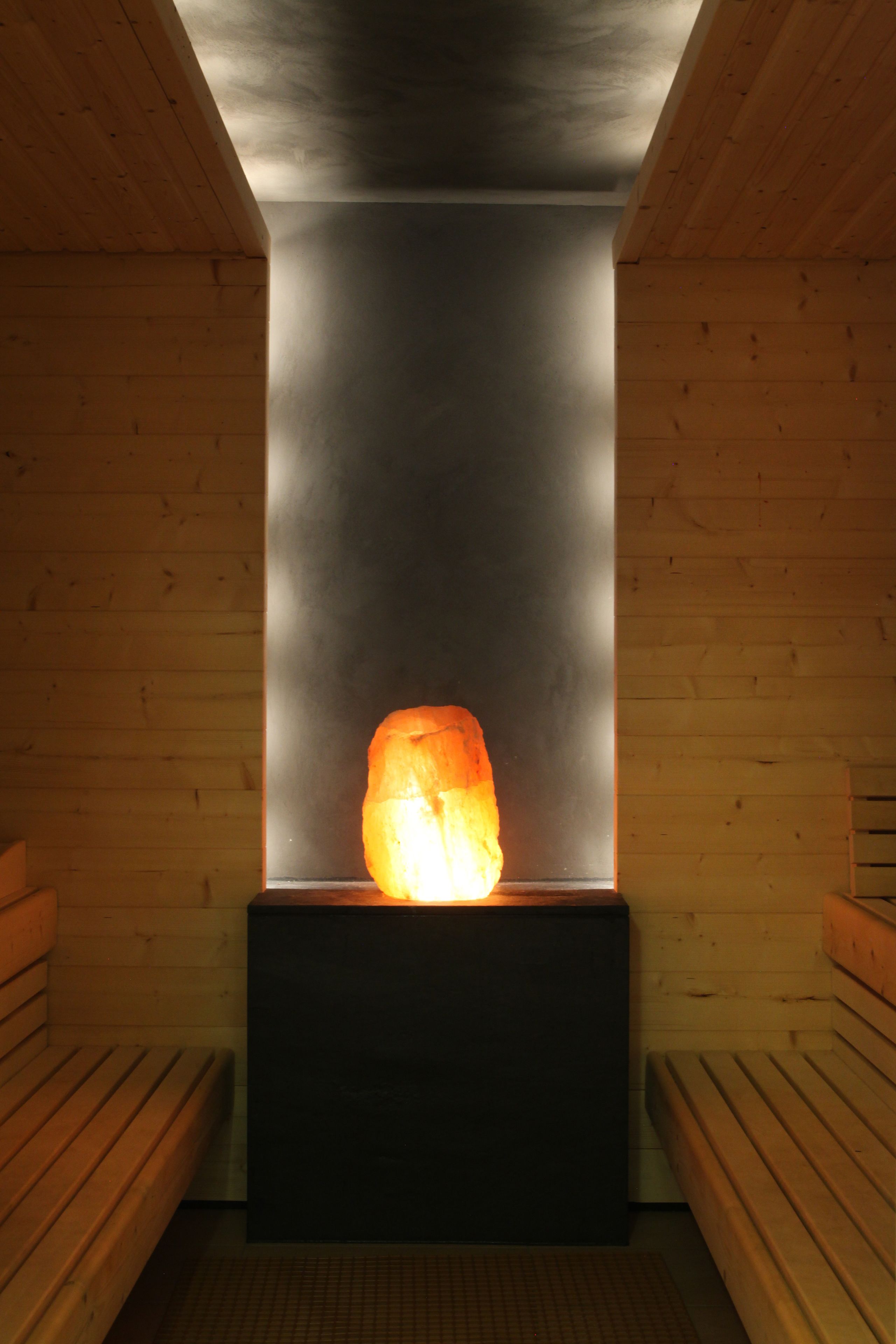 A sauna with a central heated stone, benches on either side, and wooden walls.