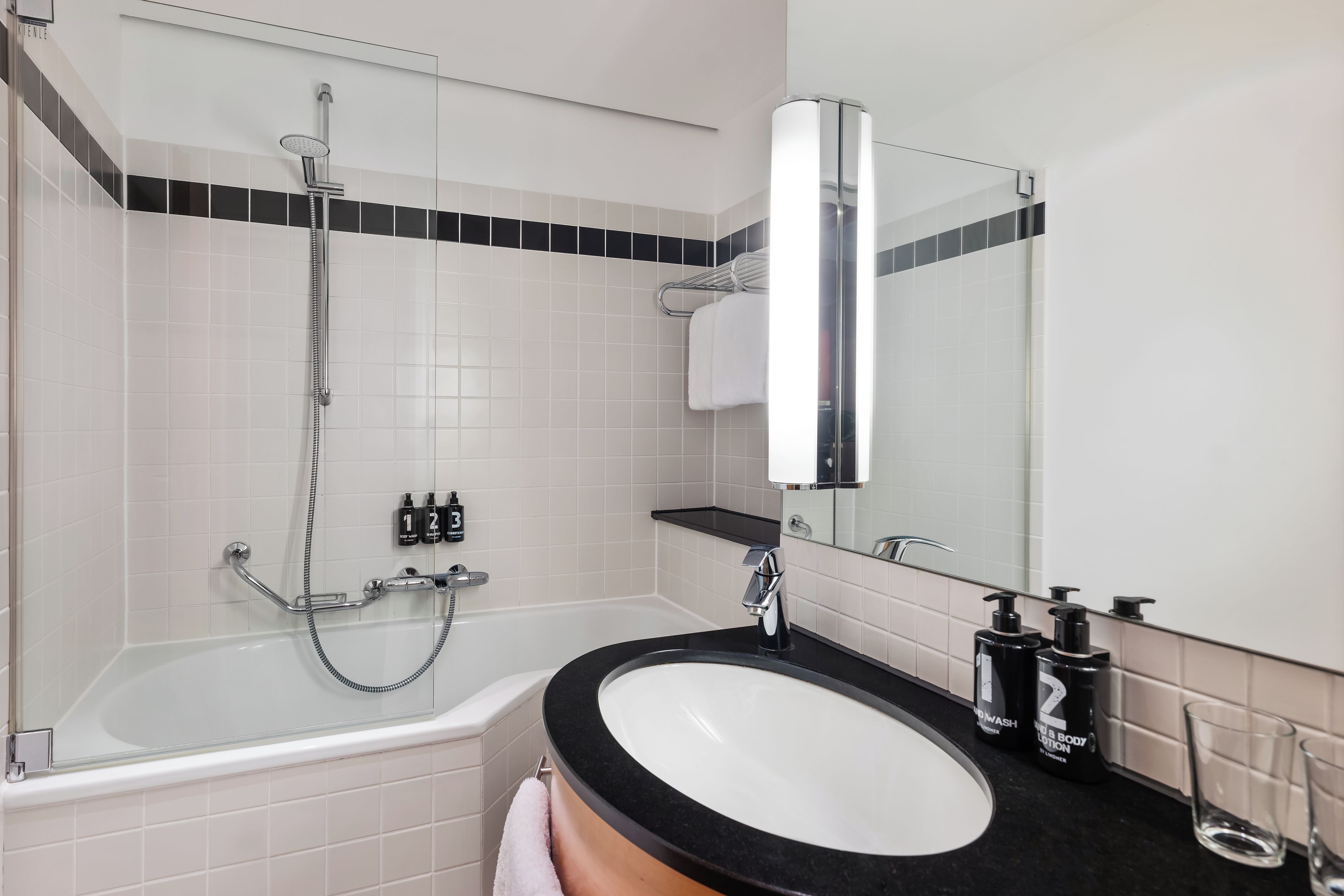 A modern bathroom with a bathtub, a shower, a sink, and a mirror.