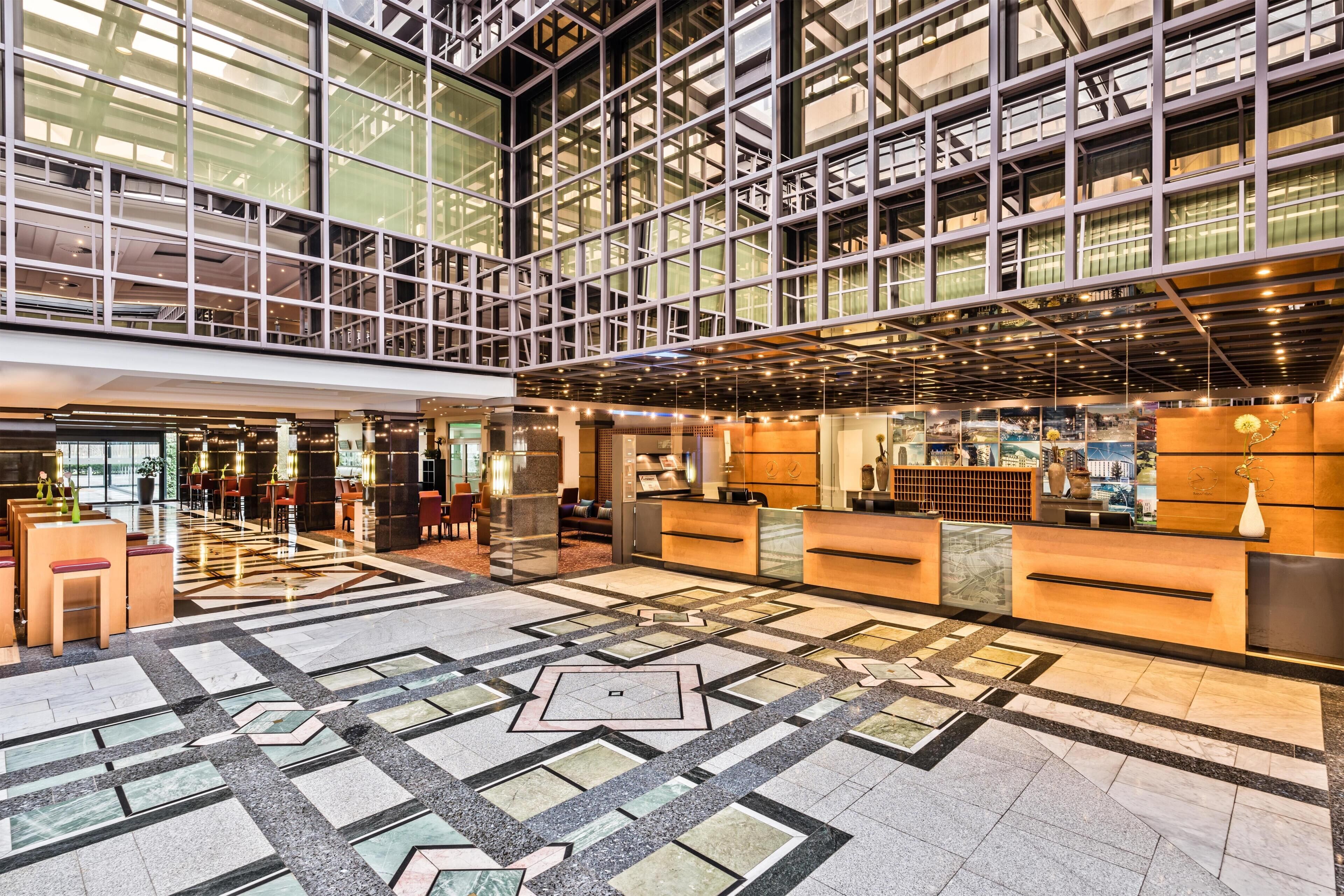 Un'ampia hall con soffitto alto, una reception e un pavimento decorato.