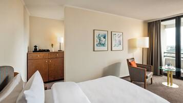 Una habitación de hotel con una cama, un escritorio con lámpara, una silla y dos cuadros en la pared.