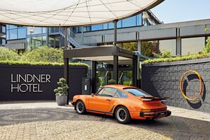 A modern hotel entrance with a Porsche parked in front. - Lindner Dusseldorf Seestern, Part of JdV by Hyatt (Düsseldorf)