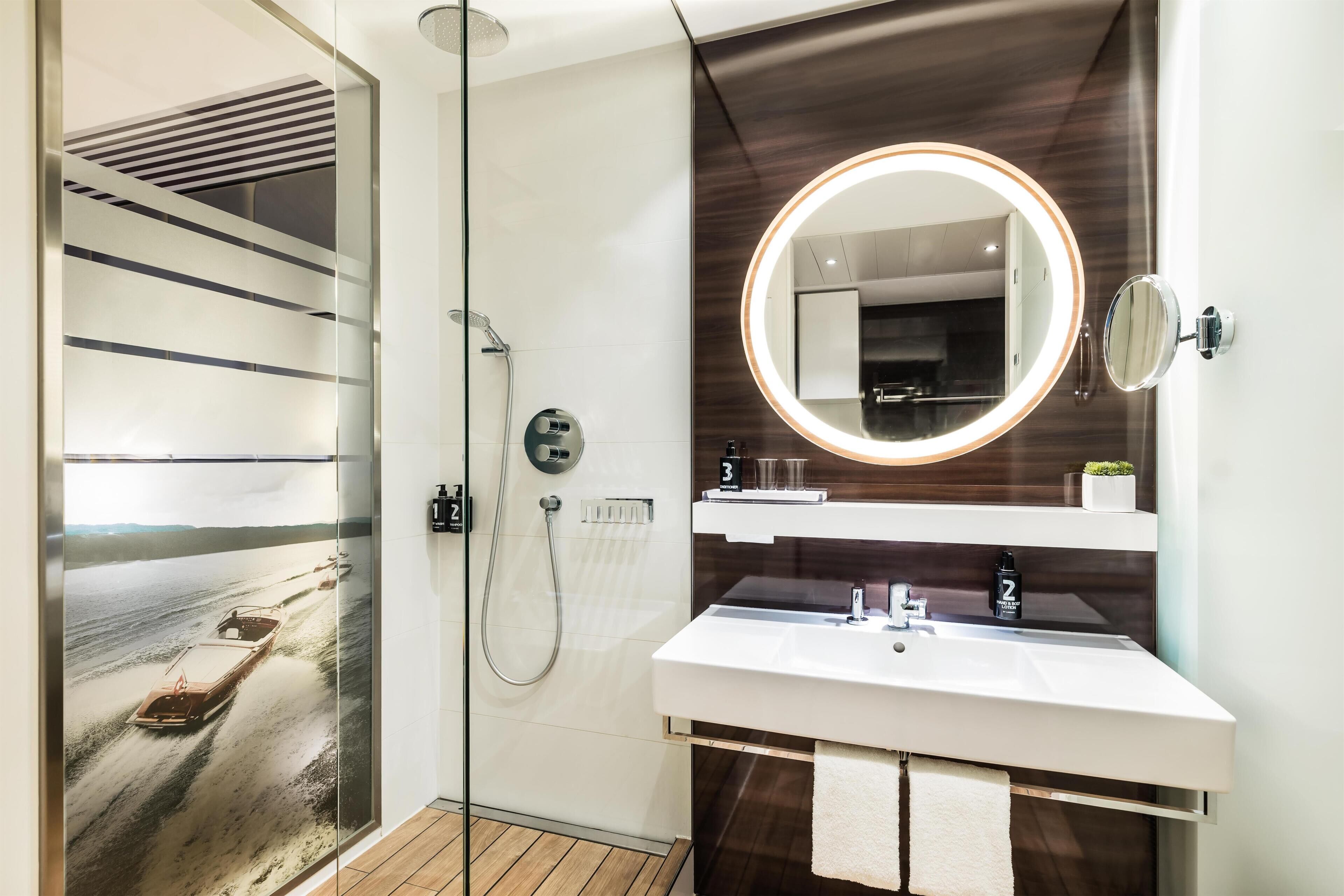 Un bagno moderno con cabina doccia in vetro, un mobile lavabo con specchio e un porta asciugamani.
