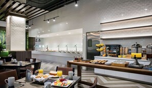 Un espace moderne dédié au petit-déjeuner, avec un buffet, des tables et des chaises confortables, et un design épuré et contemporain.