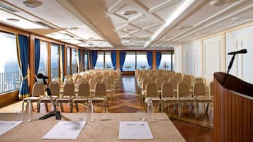 A conference room with rows of chairs, a podium, and a microphone.