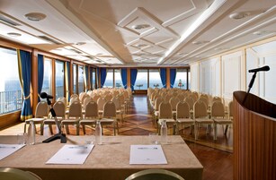 A conference room with rows of chairs, a podium, and a microphone.
