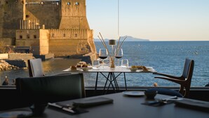 A table set for dining with a view of a historic fort and the sea. - Royal Continental Hotel Naples (Naples)