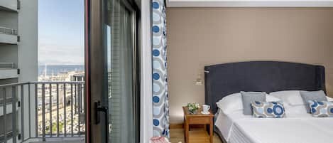 A hotel room with a bed, bedside table, and a view of the cityscape.