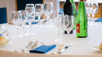 A dining table set with wine glasses, bottles, and cutlery, overlooking a marina.