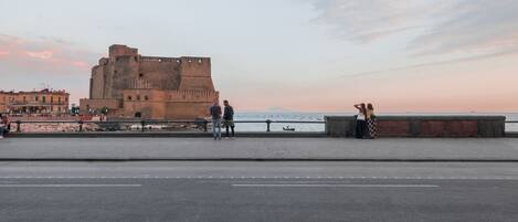 Una fortaleza histórica con un paseo pavimentado y vistas al mar.