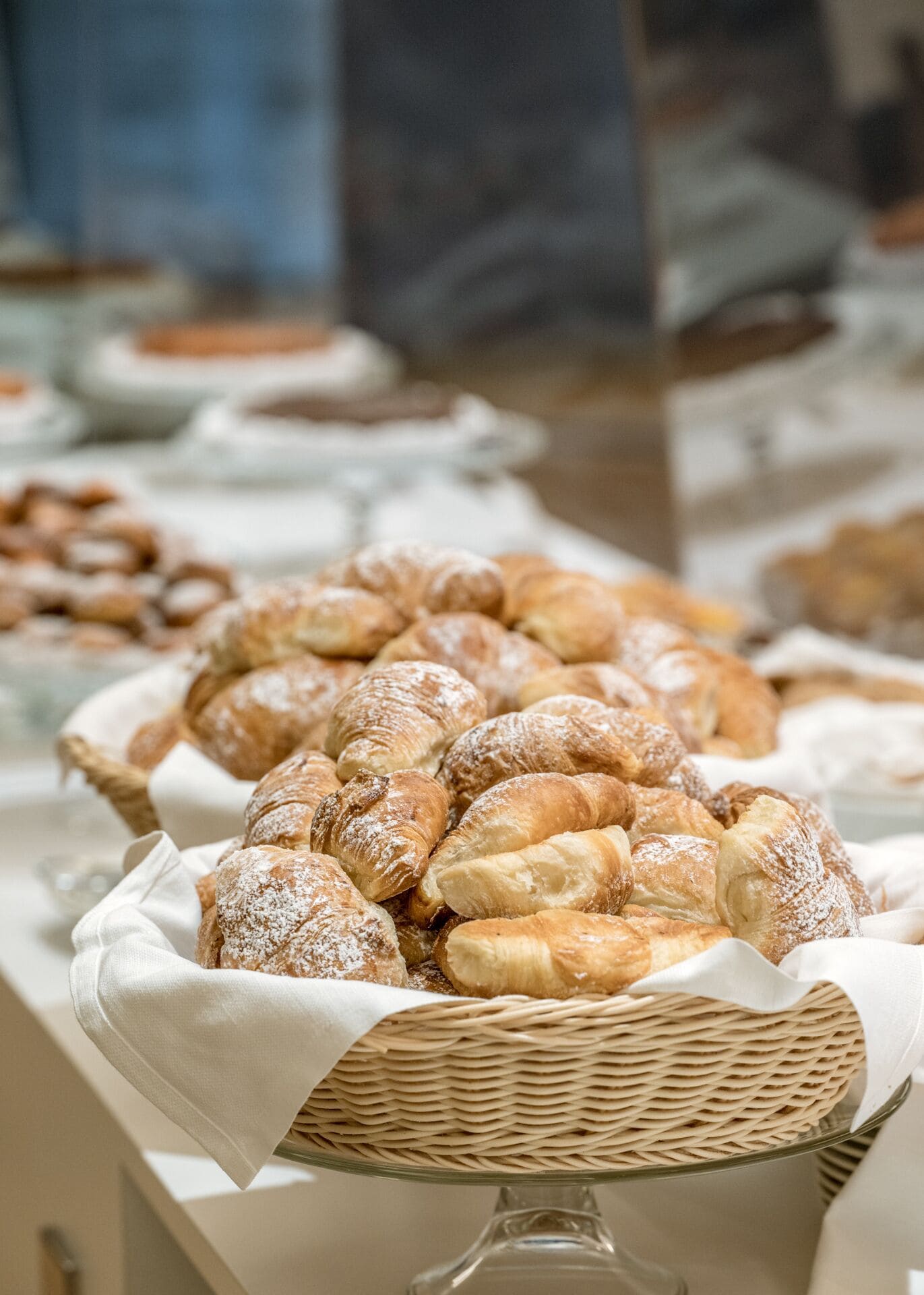A display of assorted pastries, including croissants and other baked goods, arranged on a table with a woven basket.