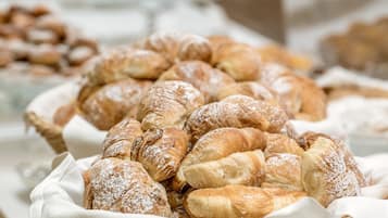 A display of assorted pastries, including croissants and other baked goods, arranged on a table with a woven basket.