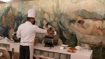 Uno chef prepara il cibo a un buffet con un grande quadro astratto sullo sfondo.