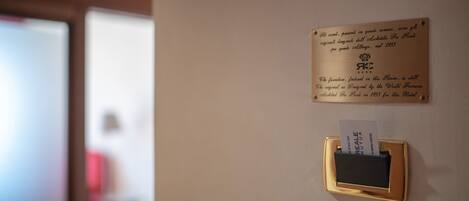 A plaque on a wall with a gold plaque holder and a card inserted into it.