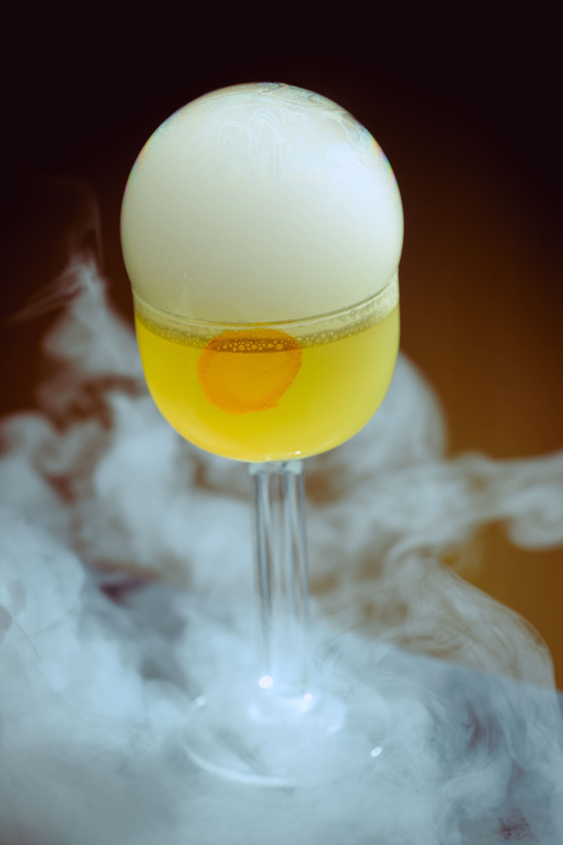 Um cocktail num copo com esquema de cores branco e amarelo, em frente a um fundo desfocado.