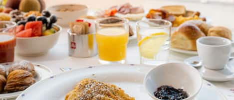 Una mesa de desayuno con diversos platos y vistas a un edificio histórico junto al agua.