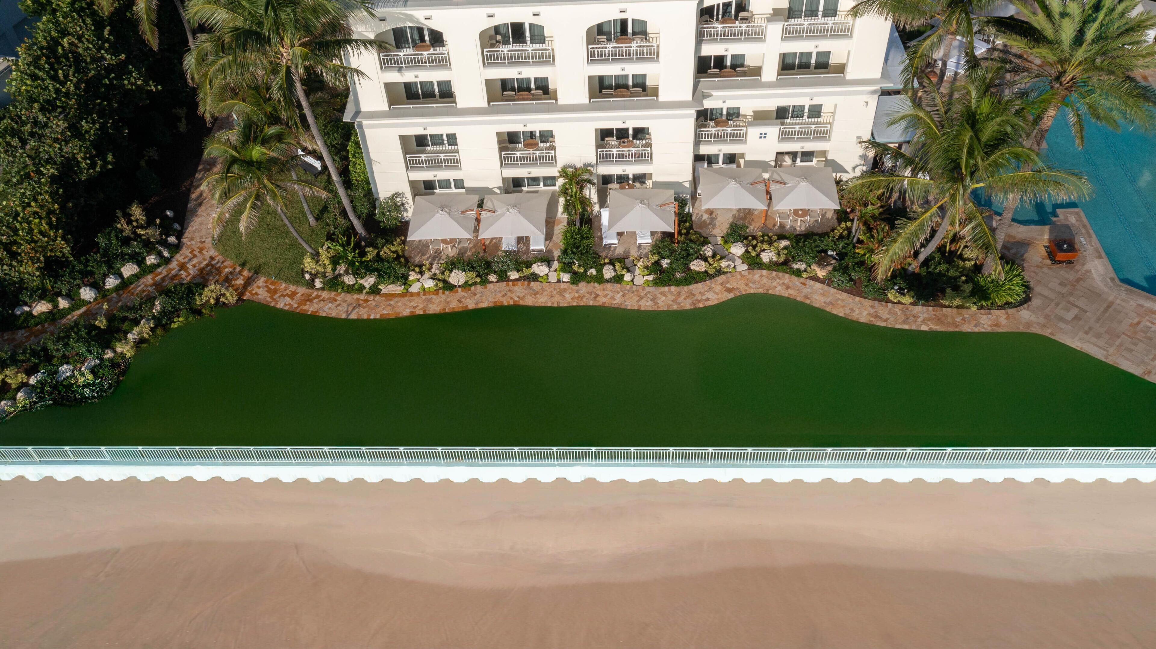 Un hôtel à plusieurs étages doté de balcons, d’une piscine et de palmiers.