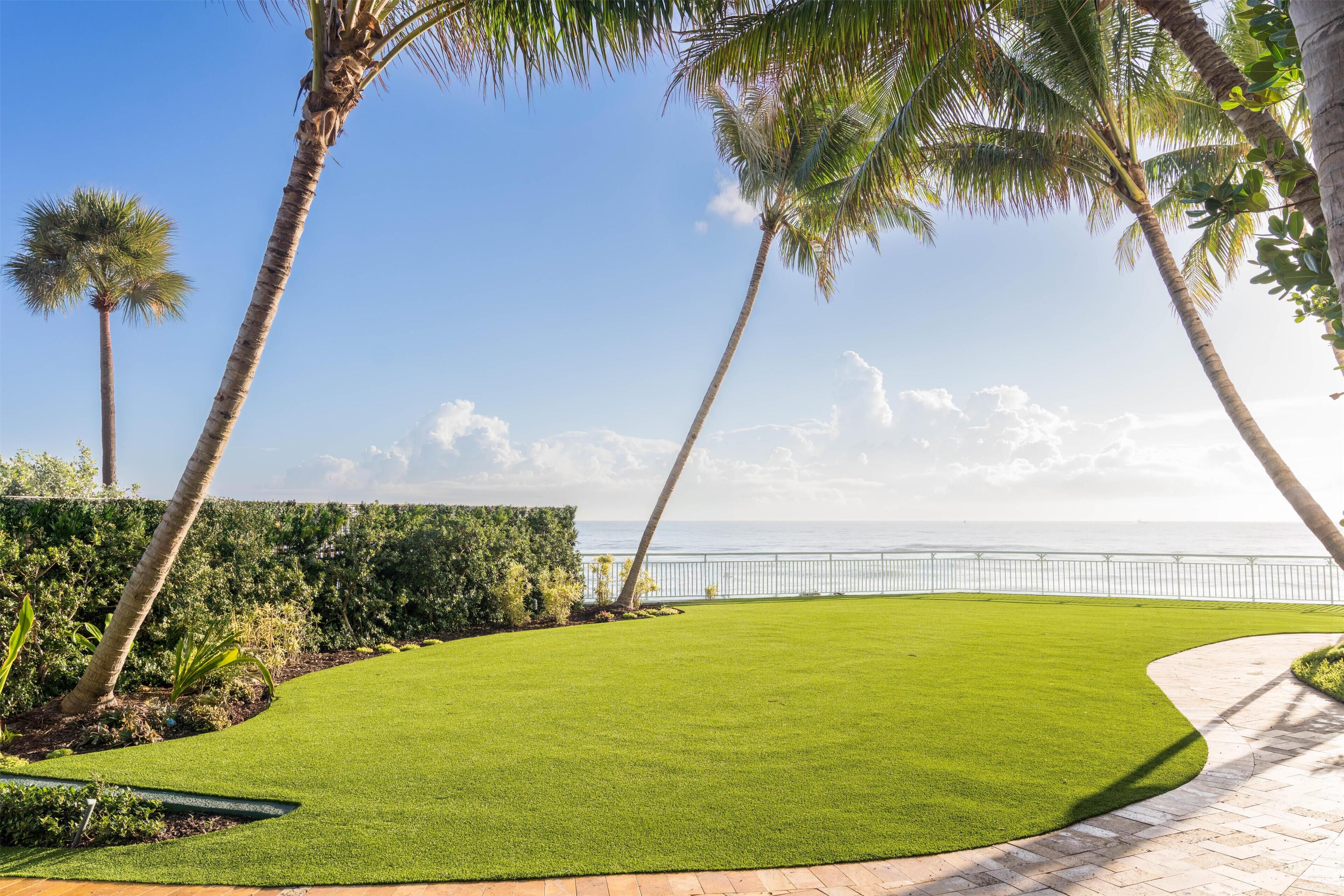 A landscaped area with palm trees, a curved pathway, and a view of the ocean.