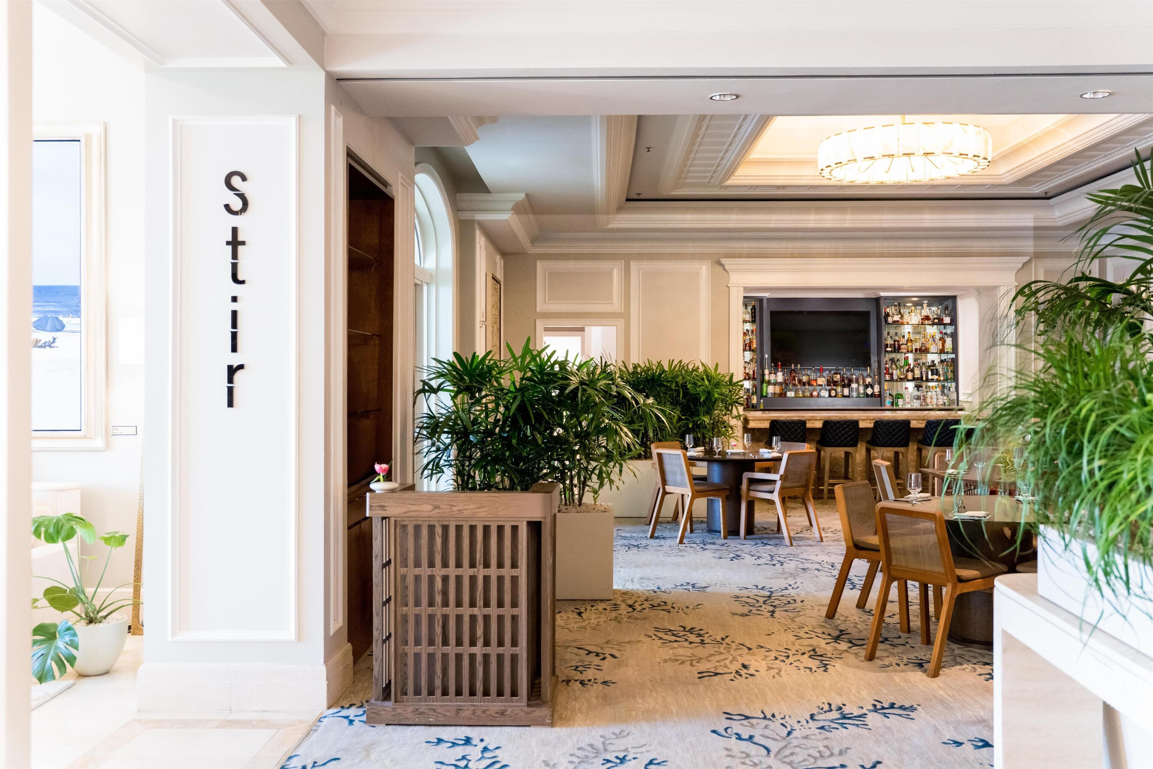 A hotel lobby with a bar area, seating, and a large plant.