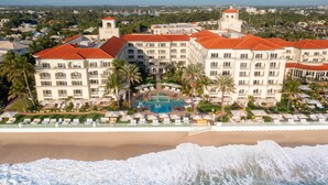 A resort with a pool, beachfront, and multiple buildings with red roofs. - Eau Resort & Spa (Manalapan)